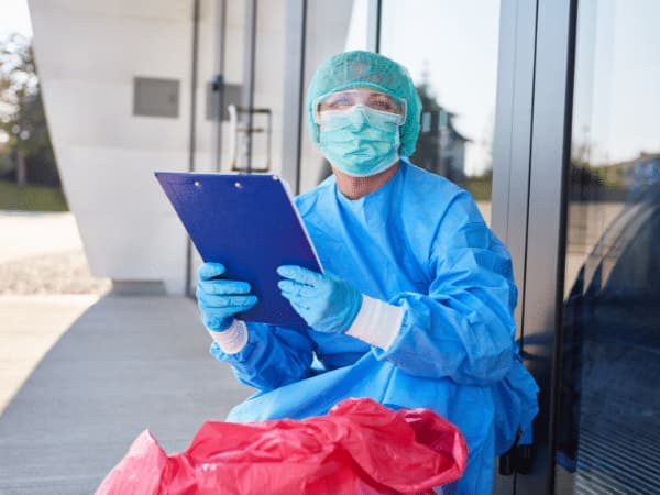 Operatore sanitario con dispositivi di protezione che verifica la documentazione per la gestione dei rifiuti pericolosi